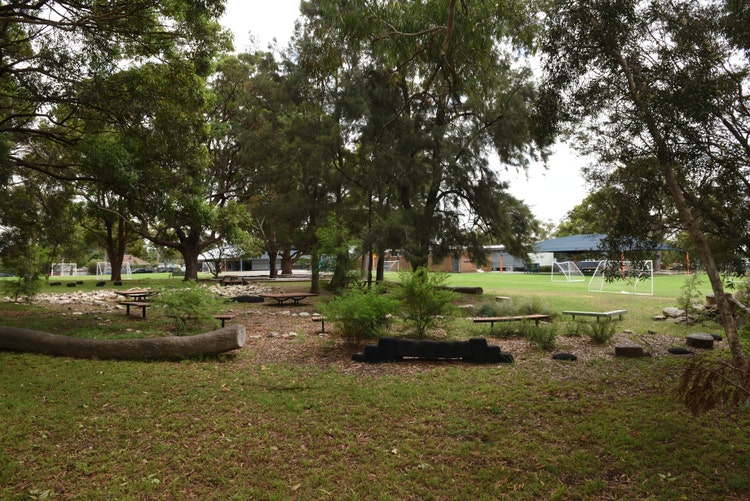 Outdoor nature area with tables and chairs amongst the trees. Somewhere for kids to take a break in a peaceful setting